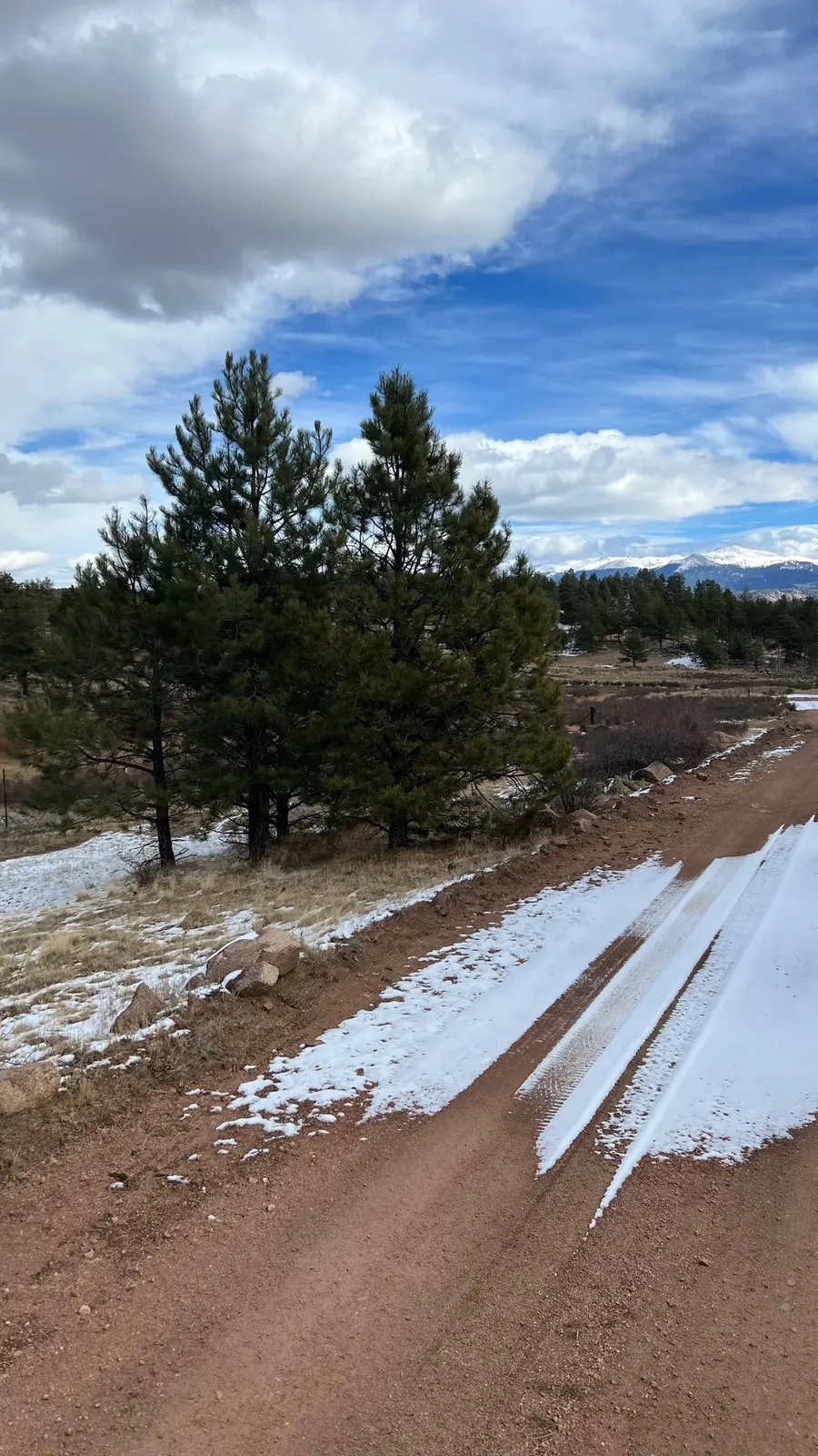 A snow-dusted ranch trail beneath blue Colorado skies.